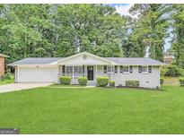 Charming single-story home with a well-manicured lawn, painted brick, and a cozy front porch at 4487 Greenleaf Sw Cir, Atlanta, GA 30331