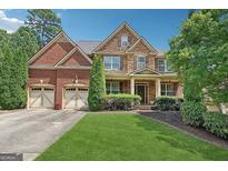 Inviting two-story home with brick and stone accents, a well-manicured lawn, and a three car garage at 2390 Colchester Ct, Cumming, GA 30041