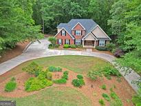 Stunning aerial view of a brick home featuring a landscaped front yard and circular driveway at 30 Joe Lee Dr, Sharpsburg, GA 30277
