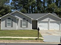 Charming one-story home features a two-car garage, symmetrical arched windows, and neutral gray siding at 6372 Stonebridge Creek Ln, Lithonia, GA 30058
