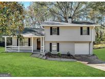 Charming split-level home featuring a front porch, well-maintained lawn, and attached garage at 3879 Mcgill Ln, Decatur, GA 30034