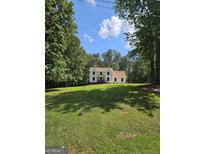 Charming two-story home with a well-manicured lawn, surrounded by lush trees, under a bright blue partly cloudy sky at 175 Forest Lake Dr, Fayetteville, GA 30215