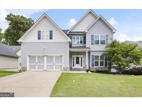 Charming two-story home featuring light gray siding, a well-manicured lawn, and a two-car garage at 1016 Buckeye Ln, Villa Rica, GA 30180