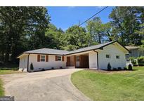 Charming brick home with a circular driveway, manicured lawn, and lush greenery, offering a welcoming curb appeal at 1939 Sandringham Sw Dr, Atlanta, GA 30311