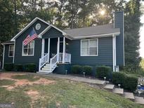 Charming single-Gathering home featuring a cozy front porch, well-kept landscaping, and an American flag at 150 Doe Run Ct, Sharpsburg, GA 30277