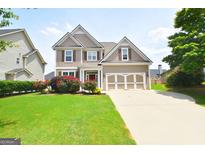 Two-story home with manicured lawn, brick accents, a two-car garage, and attractive landscaping at 613 Blackburn Ln, Peachtree City, GA 30269