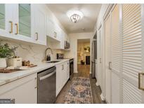 Modern kitchen features white cabinetry, stainless steel appliances, quartz countertops, and stylish backsplash at 65 Cobblestone Crk, Peachtree City, GA 30269