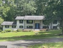 Charming two-story home with a brick facade, lush greenery, and a blue front door at 3132 Riders Trl, Decatur, GA 30034