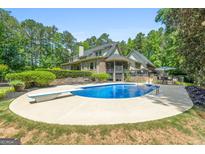 An exterior shot showcases a kidney-shaped pool with a diving board and lounge chairs surrounded by lush trees at 130 Allie Drive, Mcdonough, GA 30252