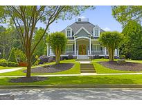Stunning home featuring a manicured lawn, charming front porch, and lush landscaping at 405 Highgrove Dr, Fayetteville, GA 30215