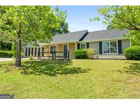 Charming single-story home with stone accents, well-manicured lawn, and lush green trees in a serene neighborhood at 1404 Meadowind Court Sw, Conyers, GA 30094