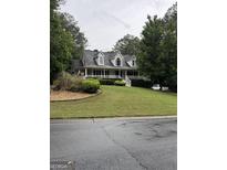 Charming two-story home with a classic design, front porch, manicured lawn, and mature trees at 212 Warrenton Dr, Douglasville, GA 30134