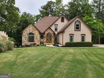 Charming home featuring stone accents, a manicured lawn, and a well-maintained landscape design at 3110 Birchton St, Johns Creek, GA 30022