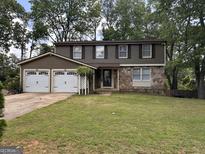 Charming two-story home with a two-car garage and stone accents in a well-maintained lawn at 1055 Worthington Hills Dr, Roswell, GA 30076
