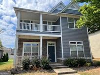 Two-story home with gray siding, stone accents, and a covered front porch and balcony at 1218 Heartwood Ave, Mcdonough, GA 30253
