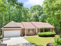 Charming brick home featuring a two-car garage, well-maintained front yard, and covered porch at 175 N Unity Grove Rd, Locust Grove, GA 30248