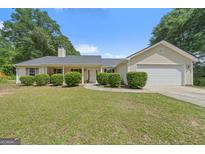 Charming single-story home featuring a manicured lawn and attached two car garage at 100 Gum Creek Landing, Oxford, GA 30054