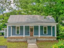Charming single-story home with a welcoming front porch and a classic metal roof at 1128 Milstead Ne Ave, Conyers, GA 30012