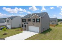 Two-story home boasts a brick facade, gray siding, attached garage, and a well-manicured lawn at 560 Whitman Ln # 2016, Stockbridge, GA 30281