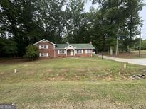Charming brick home featuring a green roof, white shutters, and a well-maintained front yard at 603 New Hope Rd, Fayetteville, GA 30214