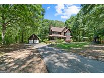 Inviting two-story home with a long driveway and a detached two-car garage nestled in a lush, wooded lot at 1627 Leguin Mill Rd, Locust Grove, GA 30248