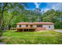 Charming ranch-style home with a red metal roof and an inviting front porch surrounded by lush greenery at 428 Cornish Mountain Rd, Oxford, GA 30054