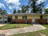 Modest single story home featuring brick and wood with a covered carport and concrete front walk at 1711 Mckenzie Dr, Decatur, GA 30032