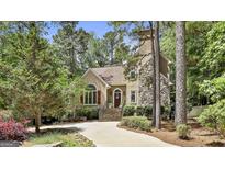 Charming home exterior featuring a stone chimney, stucco facade, and lush landscaping at 100 Rosemont, Peachtree City, GA 30269