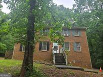 Two-story brick home with dark and teal shutters surrounded by mature trees and front yard with steps leading to the front door at 280 Benjamin Cir, Fayetteville, GA 30214