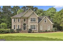 Charming two-story home featuring stone accents, a manicured lawn, and lush greenery at 604 Magnolia Ln, Peachtree City, GA 30269