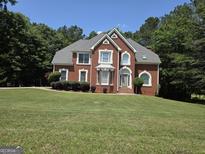Charming two-story brick home with a well-manicured lawn and mature trees on a sunny day at 308 Bell Isle, Mcdonough, GA 30252
