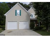 Charming home with a two-car garage, neutral stucco, and unique teal window shutters at 235 Woodstream Way, Fayetteville, GA 30214