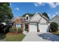 Charming single-story home with brick and vinyl siding, lush landscaping, and a two-car garage at 3350 Cooper Woods Dr, Loganville, GA 30052