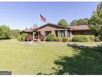 Brick home with an American flag in the front yard and well-manicured landscaping at 223 Rivers Rd, Fayetteville, GA 30214