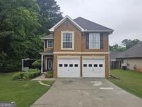 Inviting two-story home featuring a two-car garage, well-kept lawn, and charming curb appeal at 320 Weatherly Drive, Fayetteville, GA 30214