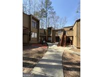 Inviting townhouse complex features a well-maintained walkway and natural surroundings on a sunny day at 5894 Par Three Ct, Lithonia, GA 30038