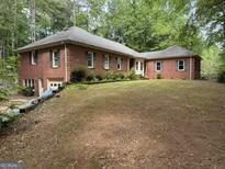 Expansive brick home with a well-manicured lawn and mature trees, offering classic charm and a serene setting at 115 Stable Creek Rd, Fayetteville, GA 30215