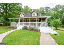 Charming home featuring a large covered porch, lush lawn, and mature trees at 3777 Edward Rd, Rex, GA 30273