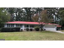 Charming, single-story home with a red roof and well-manicured front lawn and tidy landscaping at 1254 Ne Woodland Rd, Conyers, GA 30012