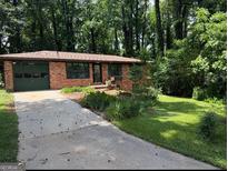 Charming brick home featuring a well-maintained lawn, lush landscaping, and a convenient attached garage at 1094 Seville Dr, Clarkston, GA 30021