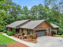 Charming brick home with a well-maintained lawn and a gray two-car garage and beautiful trees at 230 Shorewood Ct, Mcdonough, GA 30252