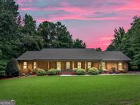Charming brick home with a long porch and landscaped front yard under a beautiful pink sunset sky at 230 Shorewood Ct, Mcdonough, GA 30252