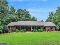 Charming brick home with a welcoming front porch, lush lawn, and mature landscaping at 230 Shorewood Ct, Mcdonough, GA 30252