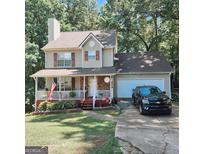 Charming two-story home featuring a welcoming front porch and attached garage, surrounded by lush trees at 190 Princeton Way, Covington, GA 30016