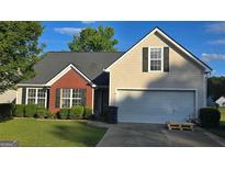Charming home showcasing a manicured lawn, a two-car garage, and traditional siding at 1525 Racquet Club Dr, Lawrenceville, GA 30043