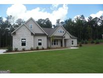 Beautiful single-story home featuring a well-manicured lawn, stone accents, and a welcoming front porch at 49 Durham Estates Dr, Sharpsburg, GA 30277