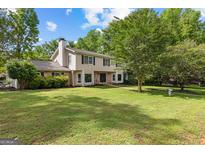 Charming two-story home featuring a lush lawn, mature trees, and a classic brick and siding facade at 101 Jasmine Path, Peachtree City, GA 30269