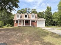 Charming brick home featuring dormer windows and an attached single car garage at 305 Anderson Cir, Covington, GA 30016