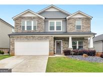 Charming two-story home with a stone and gray siding facade, manicured lawn, and attached garage at 168 Warbler Way, Mcdonough, GA 30253