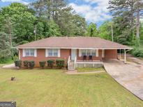 Charming single-story brick home featuring a cozy front porch and a well-maintained front yard with mature trees at 2609 Lake Harbin Rd, Morrow, GA 30260